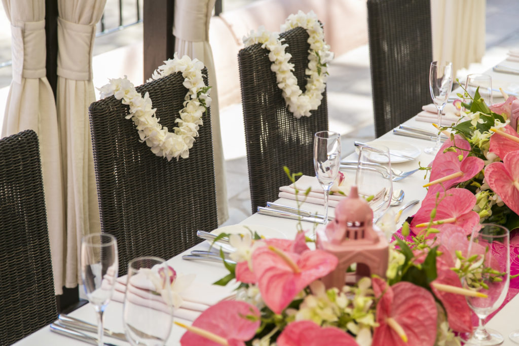 four clear champagne flutes beside pink flower on white table