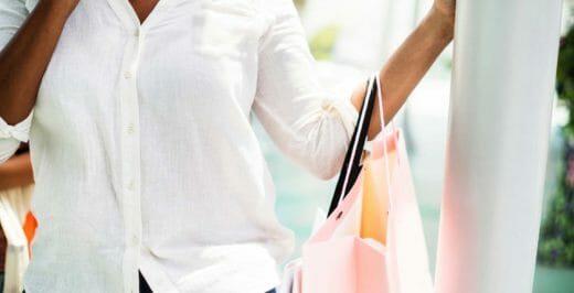woman in white button-up long-sleeved shirt standing holding pink paper bag